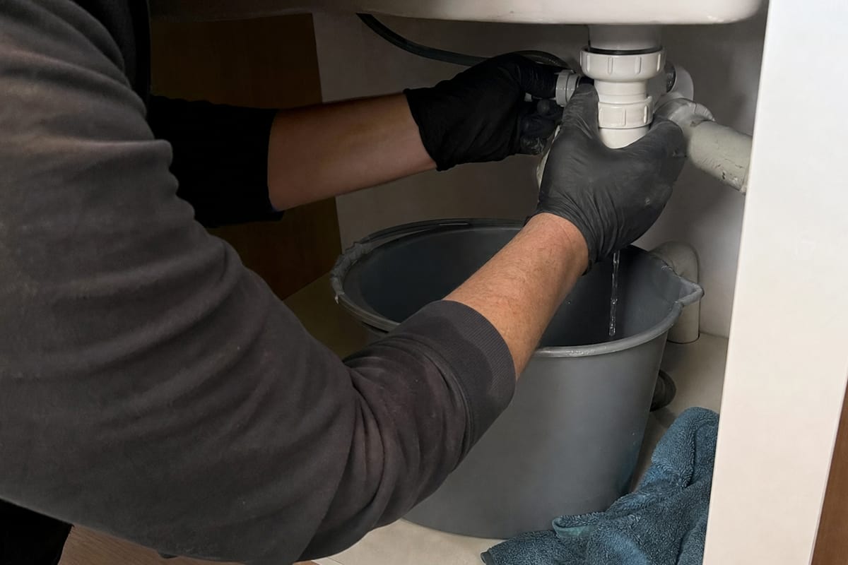 fuite d'eau sous lavabo avec mains intervenant